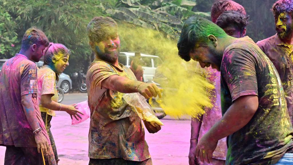Prolećni festival šarenila i plesa na ulicama Indije 2 Nekoliko momaka bacaju jedni na druge obojeni prah tokom proslave festivala Holi
