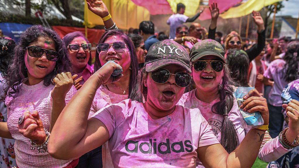 Prolećni festival šarenila i plesa na ulicama Indije 7 Nekoliko devojaka u majicama roze boje sa kačketima i naočarima za sunce