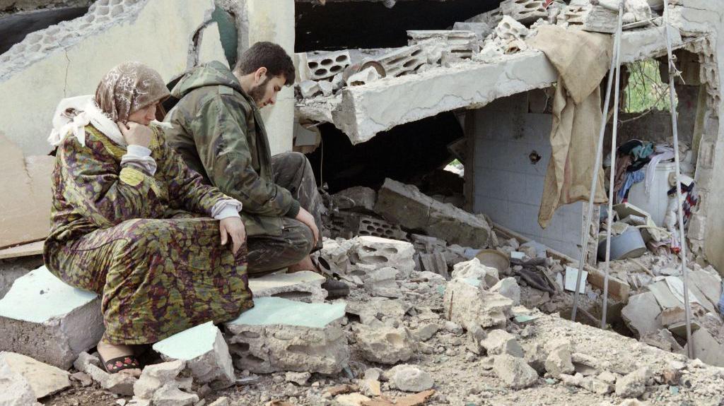 Libanski šiitski borac Hezbolaha sedi sa majkom pored njihove uništene kuće u Sidikinu, u južnom Libanu, 28. aprila 1996. godine.

