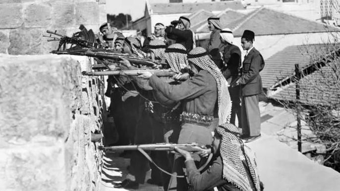 Arapska liga: Od podrške Palestini, do protivljenja ratu u Iranu 2 Crno-bela fotografija muškaraca koji drže puške nišane preko zida i preko glava imaju marame