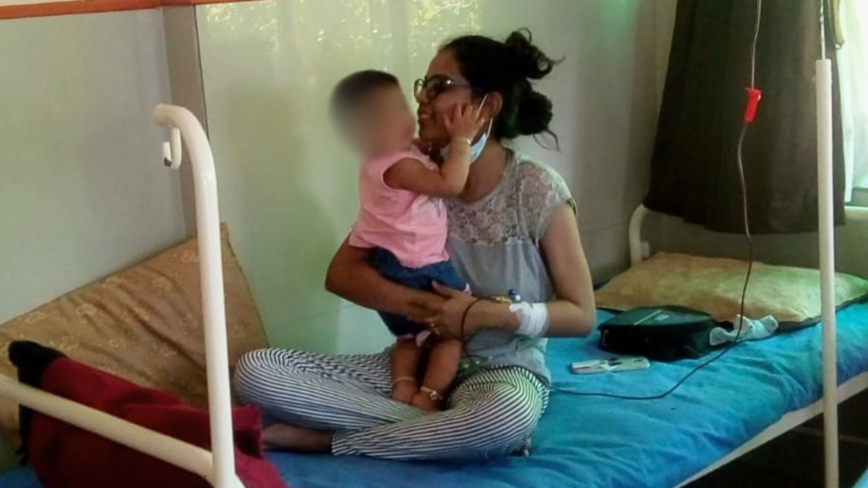 'Imala sam 36 transfuzija tokom trudnoće' 2 Kinjal is shown smiling sitting cross-legged on a metal hospital bed with a tube attached to her arm for a blood transfusion. Her baby daughter stands up in her lap