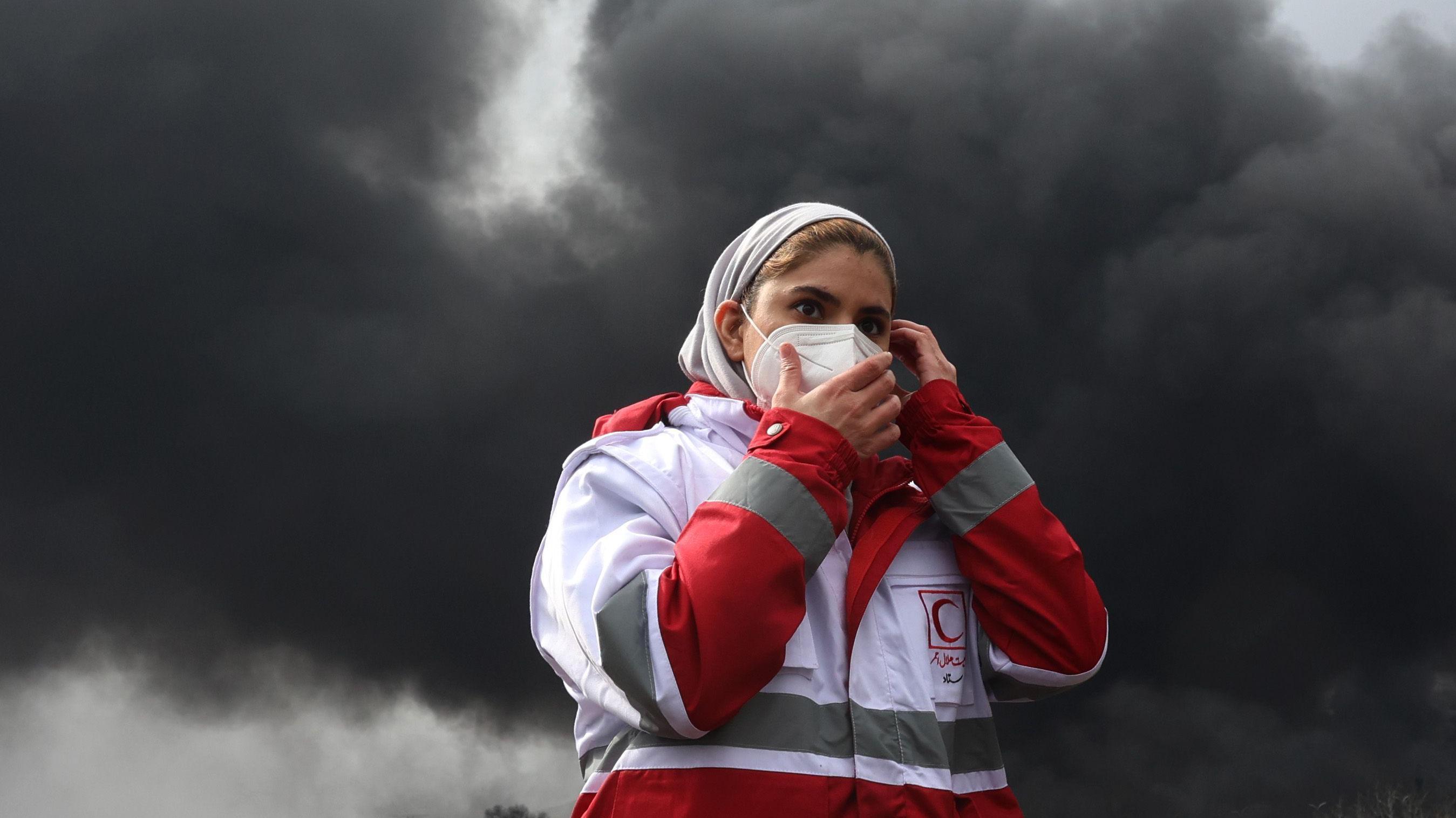'Noć se pretvorila u dan': Iranci za BBC o napadima na naftna skladišta 1 teheran, iran, pogođena naftna skladišta u iranu, žena nosi masku preko lica, a iza nje je gust dim