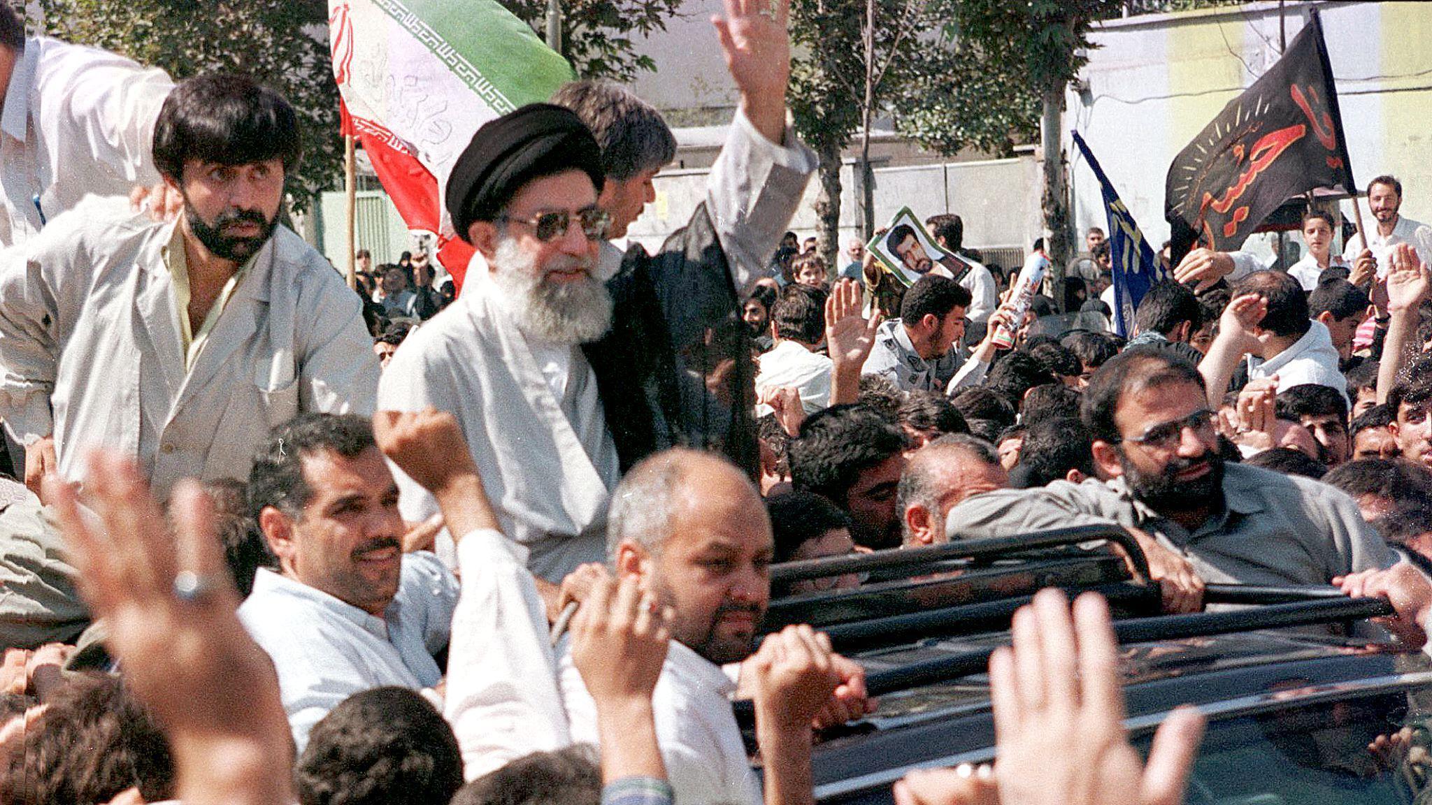 Ajatolah Hamnei: Kako je iranski vrhovni vođa držao vlast čeličnim stiskom 16 Khamenei waves to a crowd by standing up in an open-topped car on 18 September 1998 in Tehran. Several thousand Iranians took to the streets to express anger at the Taliban in Afghanistan ahead of a funeral for a group of Iranians killed by the militant group.