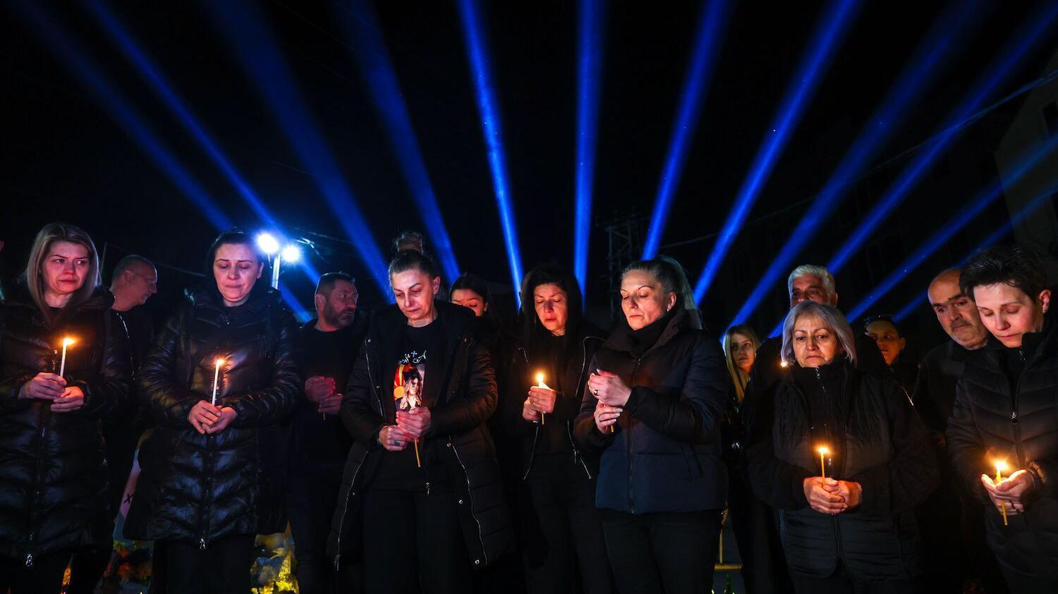 Bela srca i stolice sa imenima žrtava: Godišnjica tragedije u Severnoj Makedoniji 14 Sedam žena u crnom sa svećama u rukama, plavi snop svetlosti se vidi u daljini
