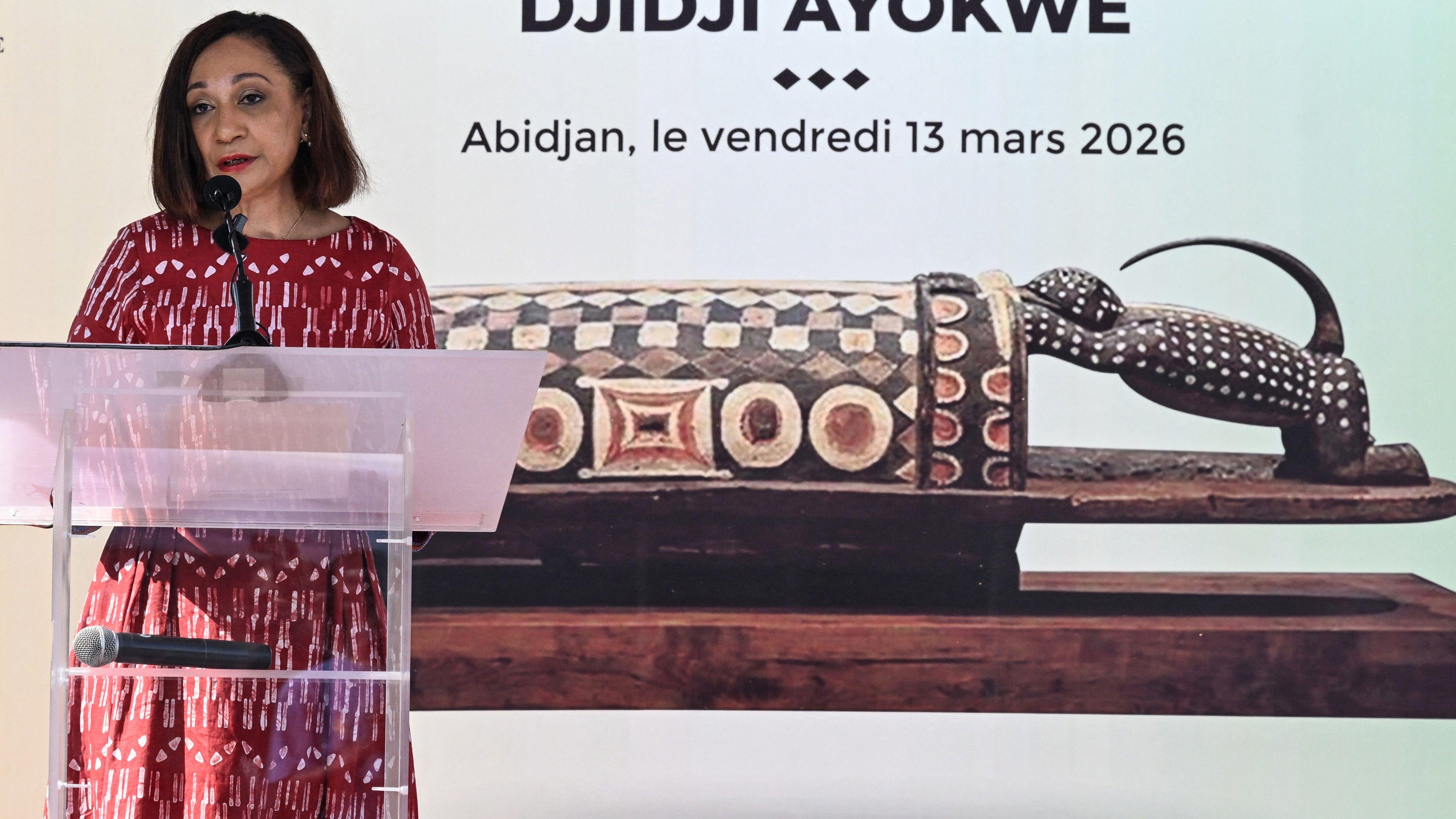 Francuzi opljačkali, pa vratili posle više od veka: 'Sveti bubanj' stigao kući 1 Ivorian Minister of Culture and Francophonie Françoise Remarck talks at a podium in front of a picture of the ornately carved wooden drum