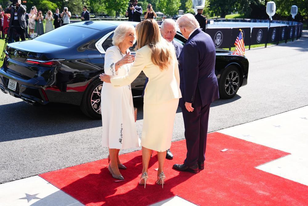 Gardisti, čaj i pčele: Prva zvanična poseta britanskog kraljevskog para Americi 6 Kamila u beloj haljini se pozdravlja sa Melanijom Tramp u krem kostimu. Pored njih Čarls i Tramp u odelima