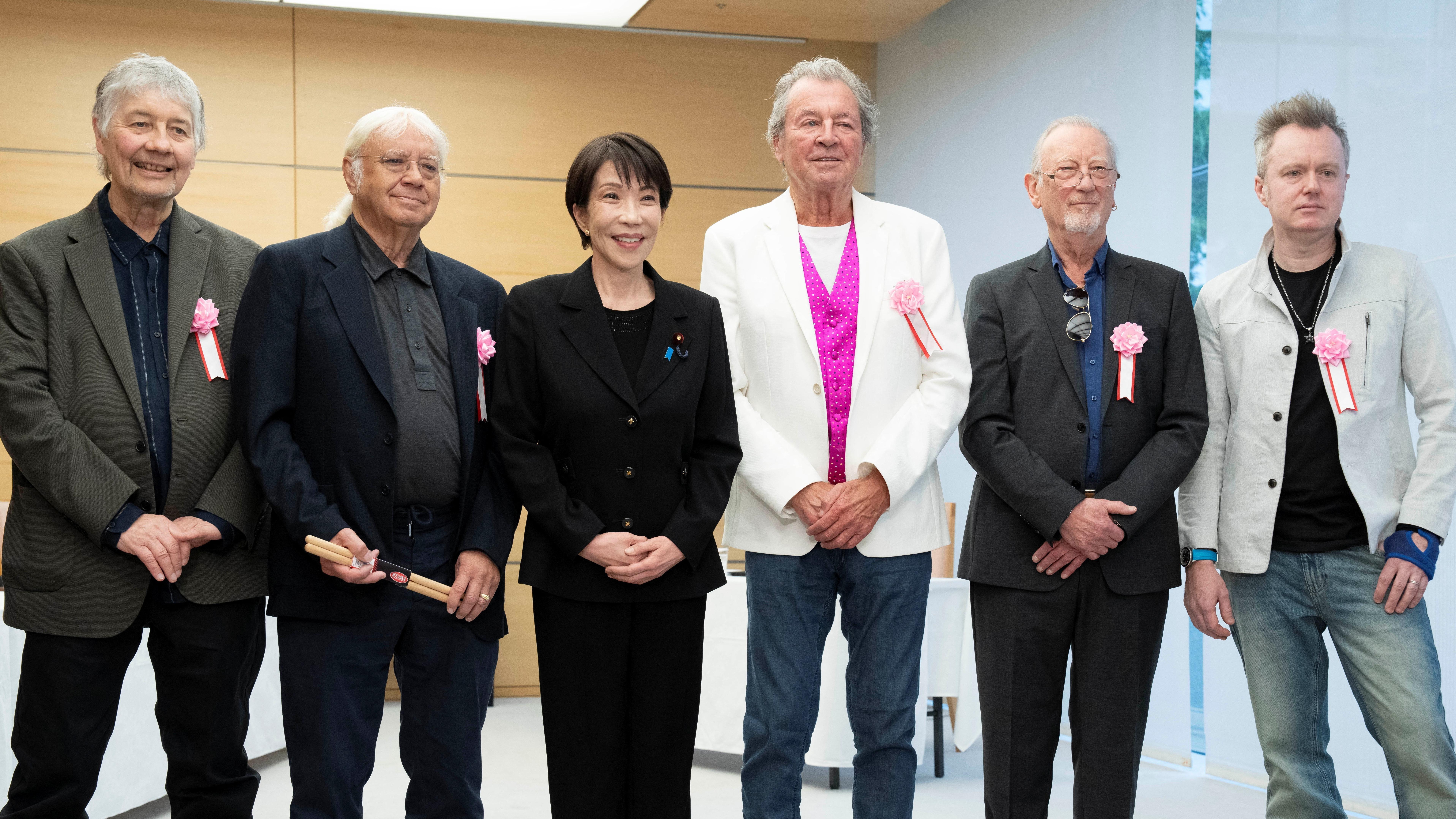 'Ti si moj bog': Susret premijerke Japana i članova benda Dip Parpl 2 Takaiči u crnom sakou i suknji nasmejano pozira sa članovima benda. S leva na desno su: Don Ejri, Ijan Pejs, Sanae Takaiči, Ijan Gilan, Rodžer Glover i Sajmon Mekbrajd
