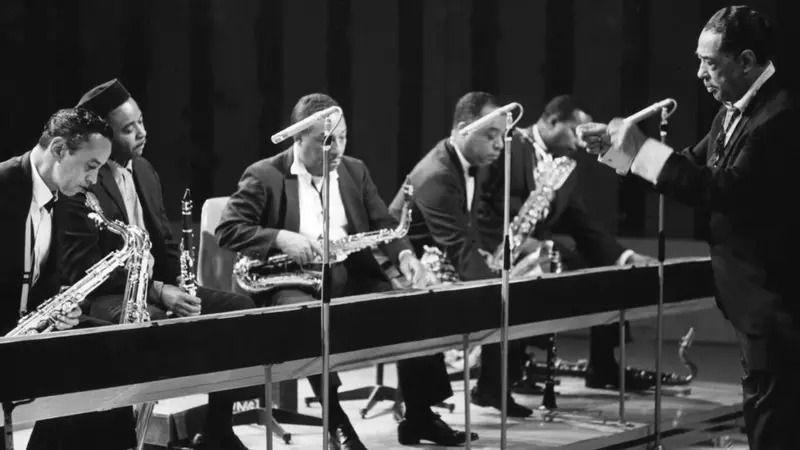Kako su se zavoleli Djuk Elington i Beograd 4 Djuk Elington u odelu diriguje orkestrom u prvim redovima nekoliko muzičara sa saksofonima