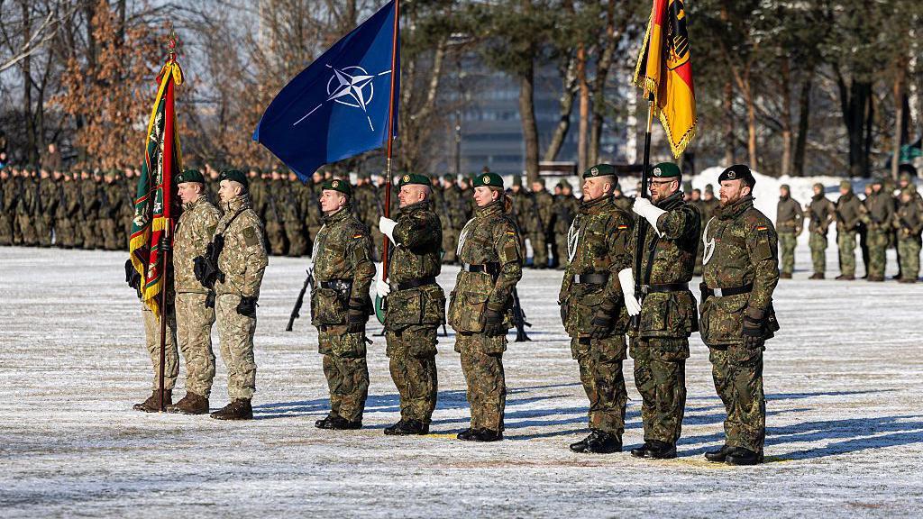 Može li NATO da bude ubedljiva sila bez Amerike 4 Nemački vojnici u zelenim kamuflažnim uniformama na paradi i sa zastavom NATO-a tokom ceremonije povodom proširenja nemačkog vojnog angažmana u Litvaniji 4. februara 2026. u Kaunasu