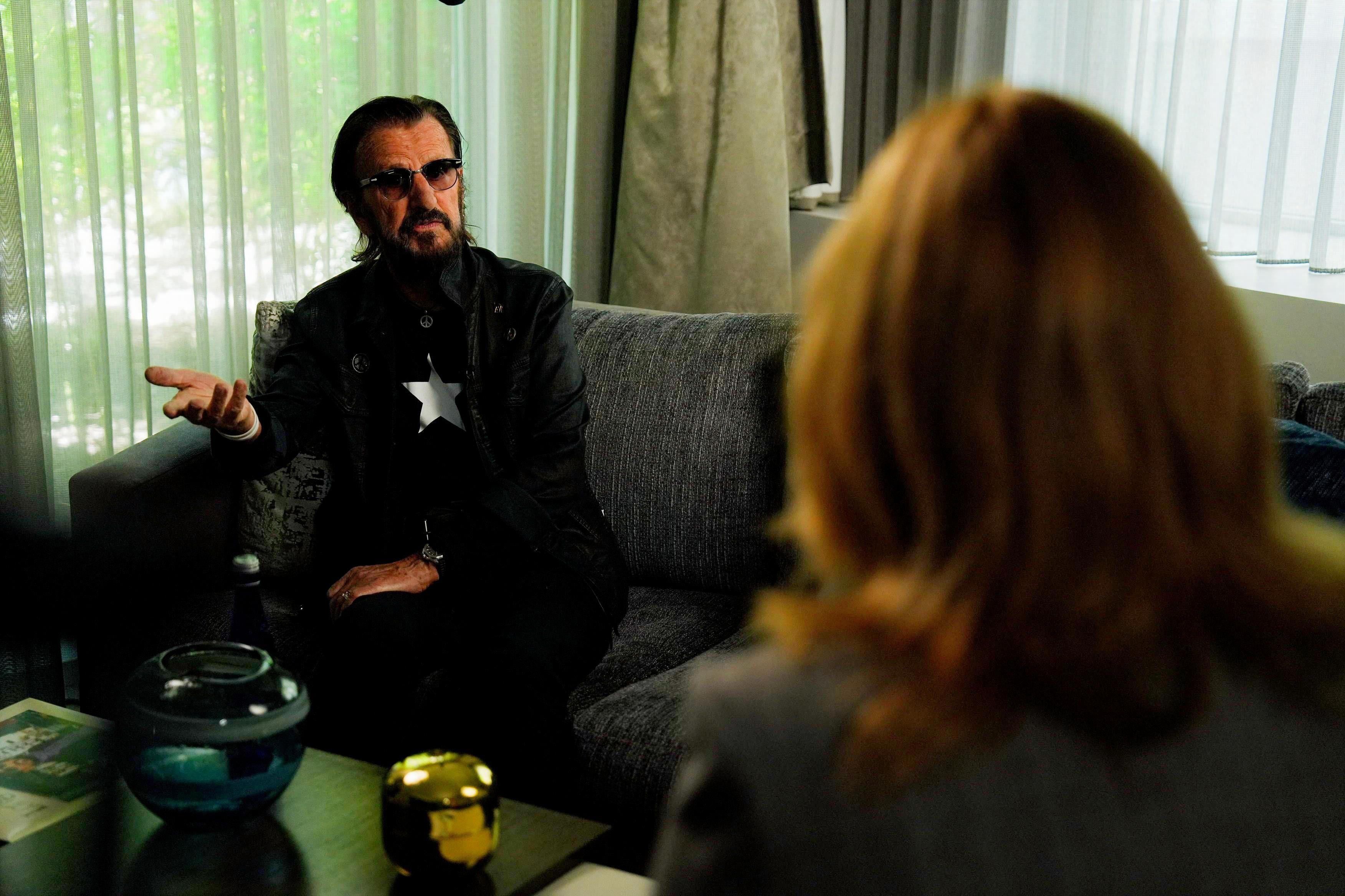 Od Bitlsa do kantri albuma: Legendarni bubnjar Ringo Star za BBC 2 Ringo Star u prvom planu sedi na kauču i razgovara sa ženom okrenutom leđima ka kameri