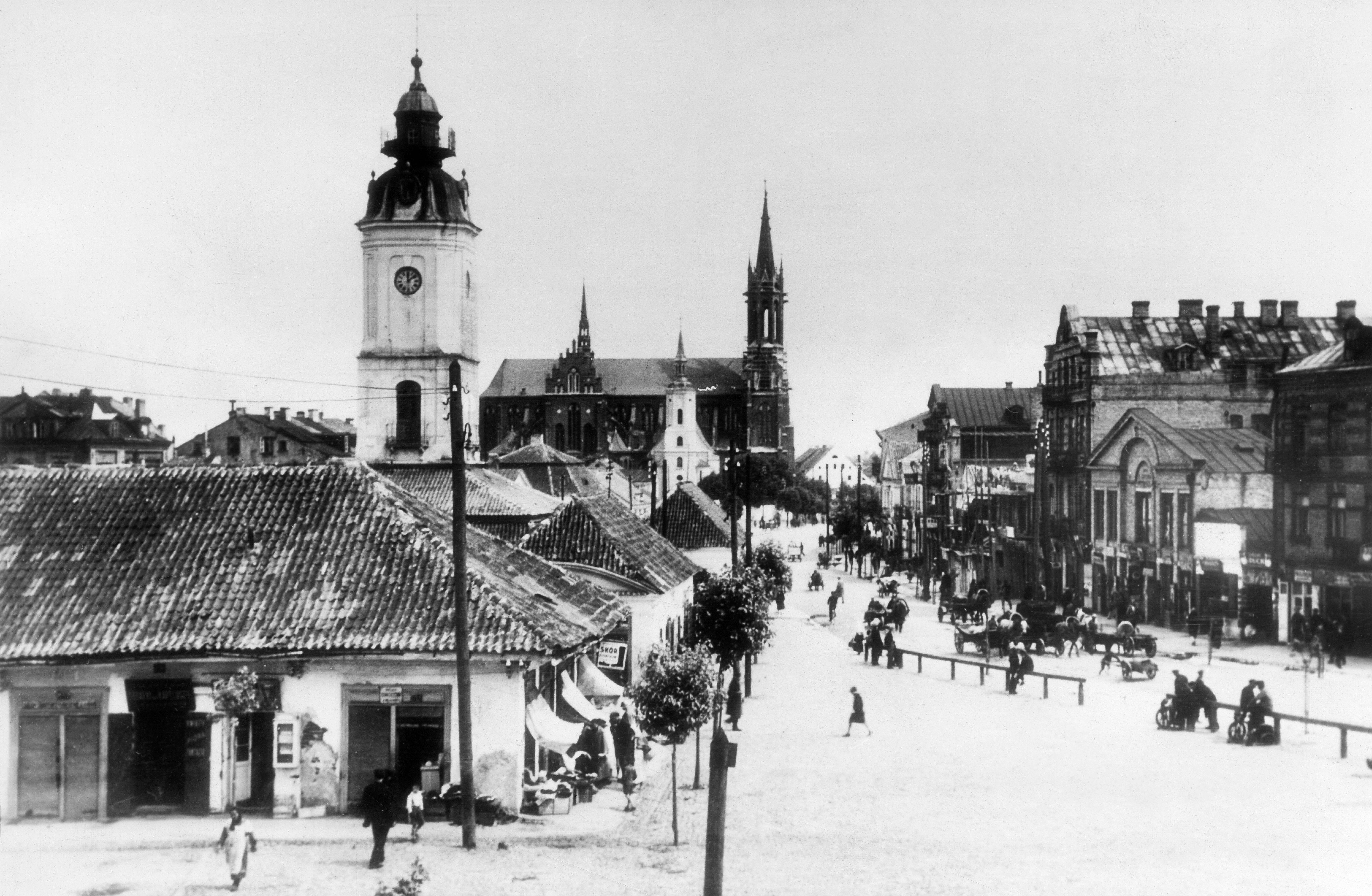 'Verovala sam da su mi preci antifašisti, a onda sam otkrila da je pradeda bio nacista' 7 Ugao ulice sa zgradom sa kosim krovom i tornjem. Nadstrešnice se protežu iznad trotoara sa jedne strane. Visoka zgrada sa tornjem je u daljini, a iza ograde sa druge strane ulice nalaze se zgrade različitih visina. Nekoliko ljudi hoda ulicom koja izgleda kao da je prekrivena snegom.