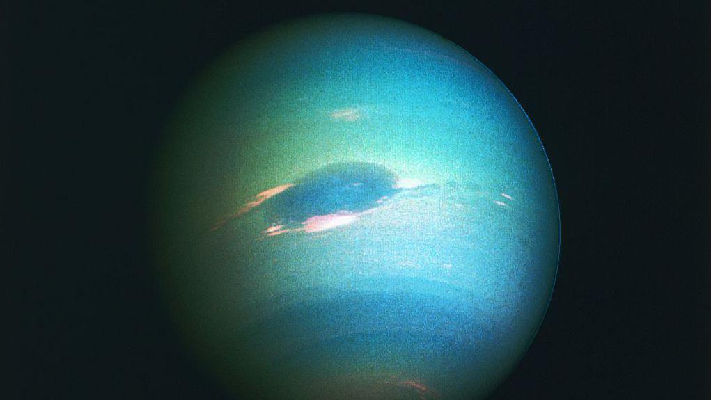 Jesmo li blizu rešenja misterije 'devete planete' Sunčevog sistema 5 Neptun se vidi osvetljen kao skoro puna sfera, sa različitim nijansama zelenkasto-plavih traka preko površine i velikom tamnoplavom ovalnom površinom u sredini.