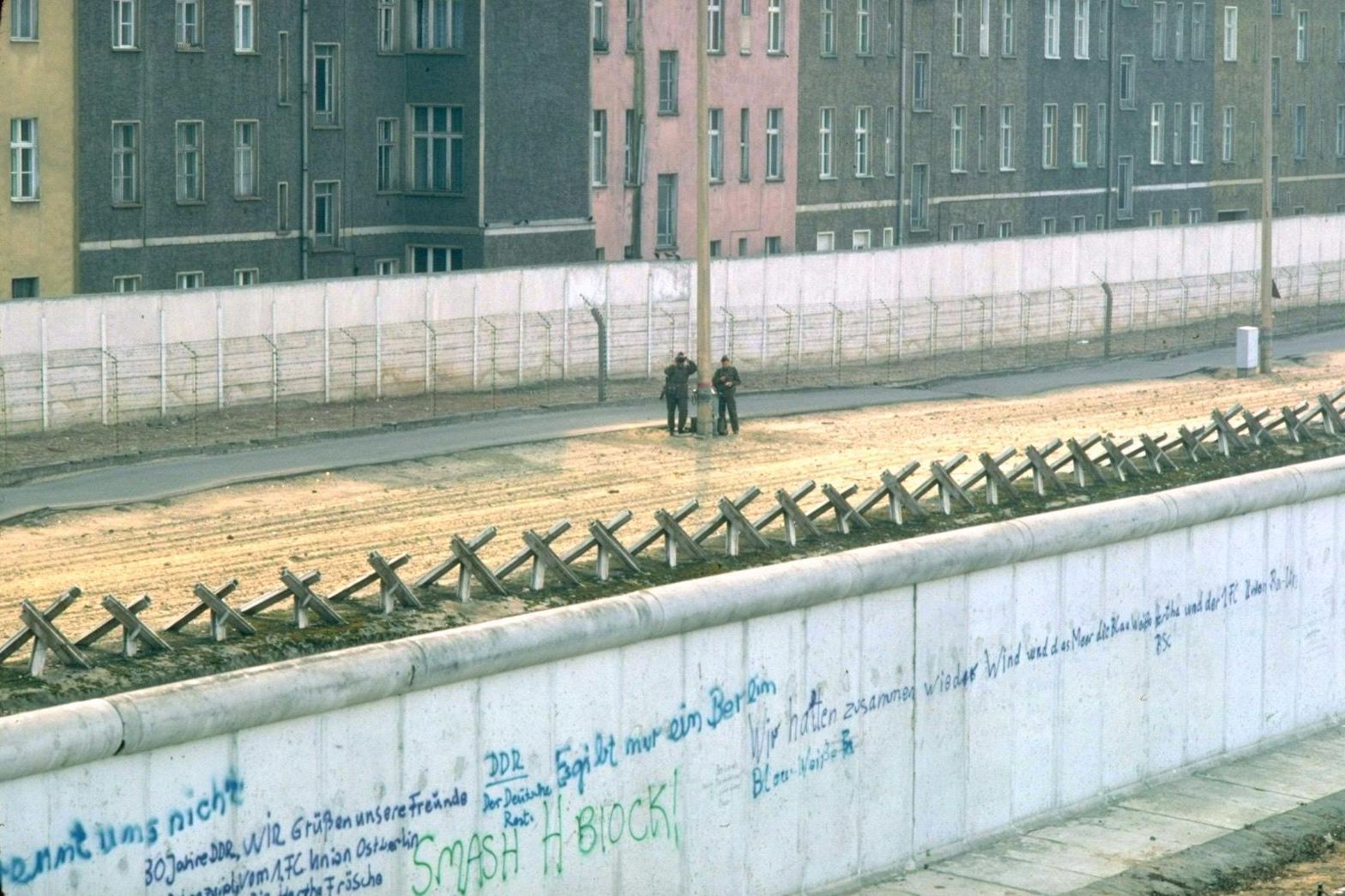 'Verovala sam da su mi preci antifašisti, a onda sam otkrila da je pradeda bio nacista' 4 Beli betonski Berlinski zid 1. marta 1982. godine, sa ispisanim grafitima. Sa druge strane zida je deo neplodne zemlje sa dva istočnonemačka stražara, metalnom ogradom, još jednim belim betonskim zidom, a zatim zgradama u Istočnom Berlinu.