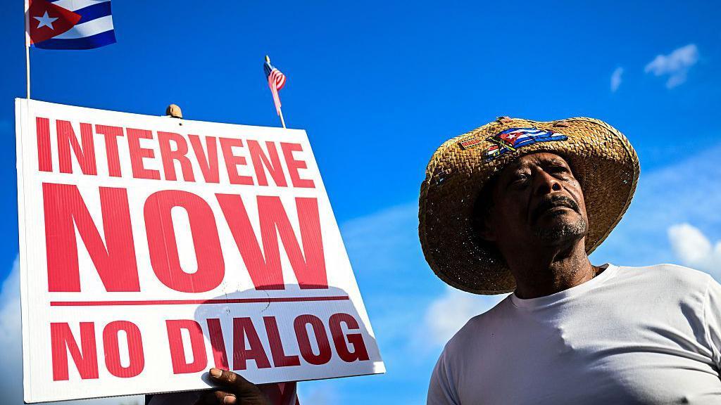 Tri načina na koja bi se mogla odvijati nova američko-kubanska kriza 1 Man holding an "intervene now" sign in Miami, Florida.