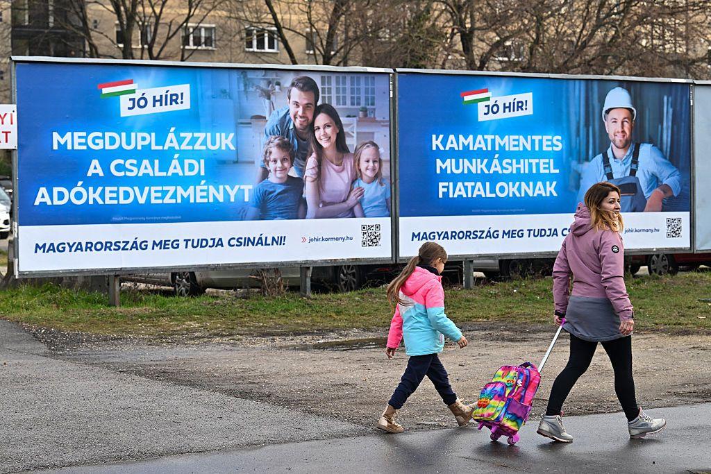 Mađarska 'prilagođena porodici': Nagrada za parove sa bebama, dugovi do guše za ljude bez dece 6 Majka prolazi sa ćerkom pored bilborda na kojima se reklamira populaciona politika države