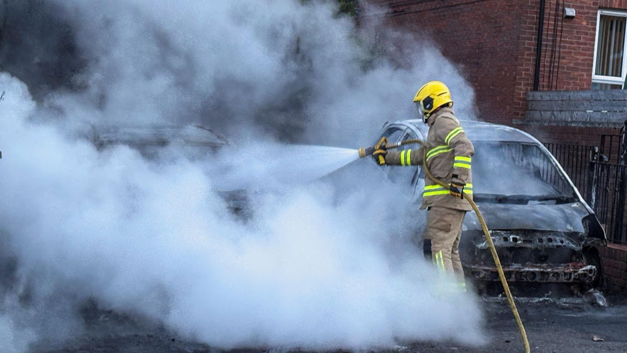 Druga noć nereda: Vodeni topovi i zapaljena vozila na ulicama Belfasta 3 vatrogasac gasi zapaljeni automobil