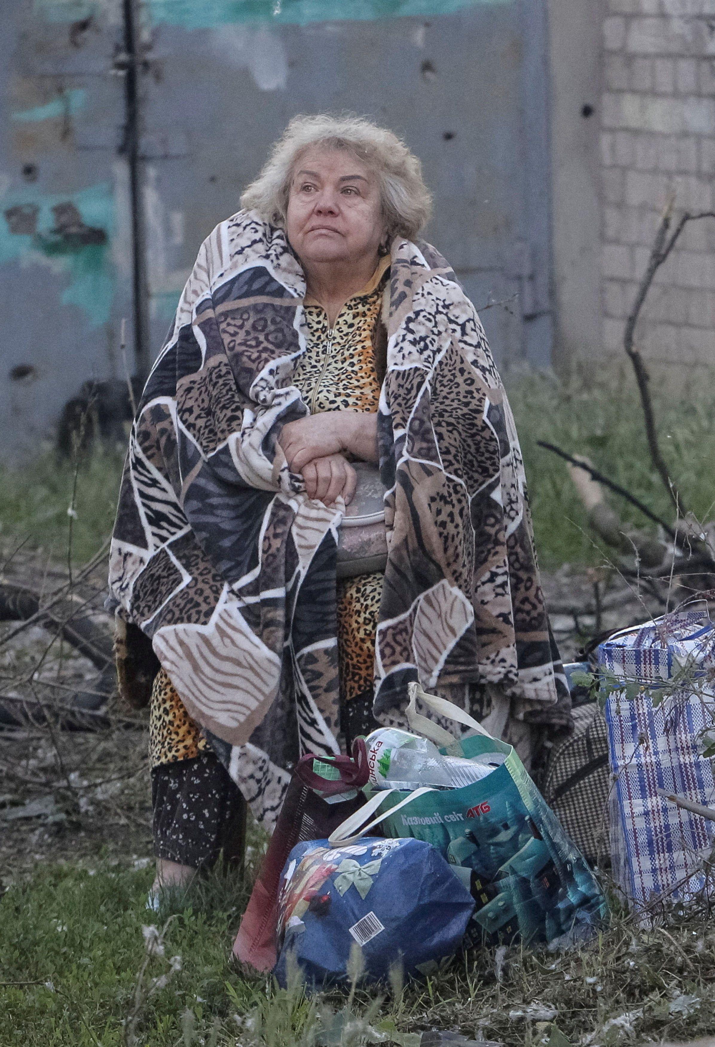 Ruski napadi širom Ukrajine: Dvoje dece među 22 žrtve, više od 100 povređenih 11 napad na ukrajinu, žena umotana u ćebe stoji na travi posle ruskog napada na dnjepar