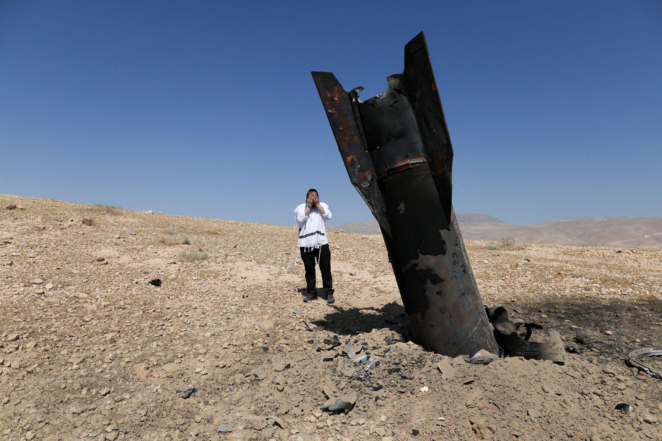 Izrael i Iran za sada obustavljaju međusobne napade, Tramp tvrdi da on 'vuče sve poteze' 1 Fotografija čoveka kako stoji pored rakete koja se zabila u zemlju