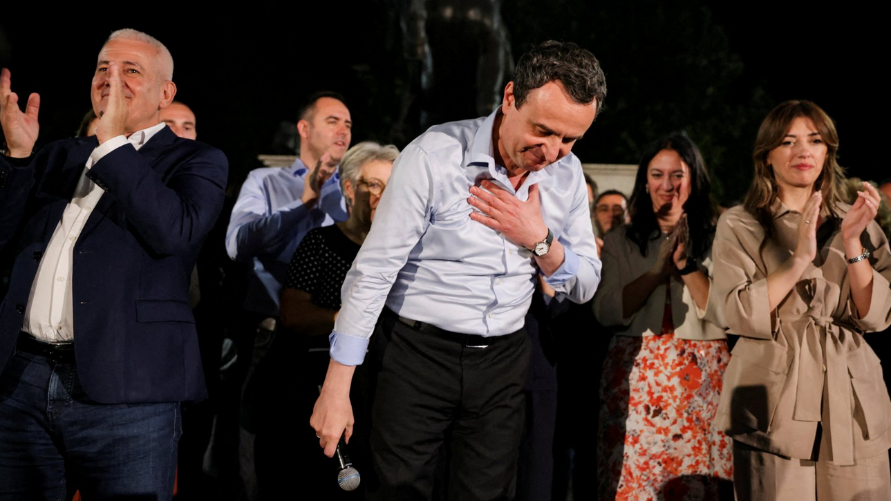 Izbori na Kosovu: Još jedna pobeda Samoopredeljenja, ali bez većine u parlamentu 1 Muškarac u košulji se poklanja publici, iza njega ljudi, u ruci drži mikrofon