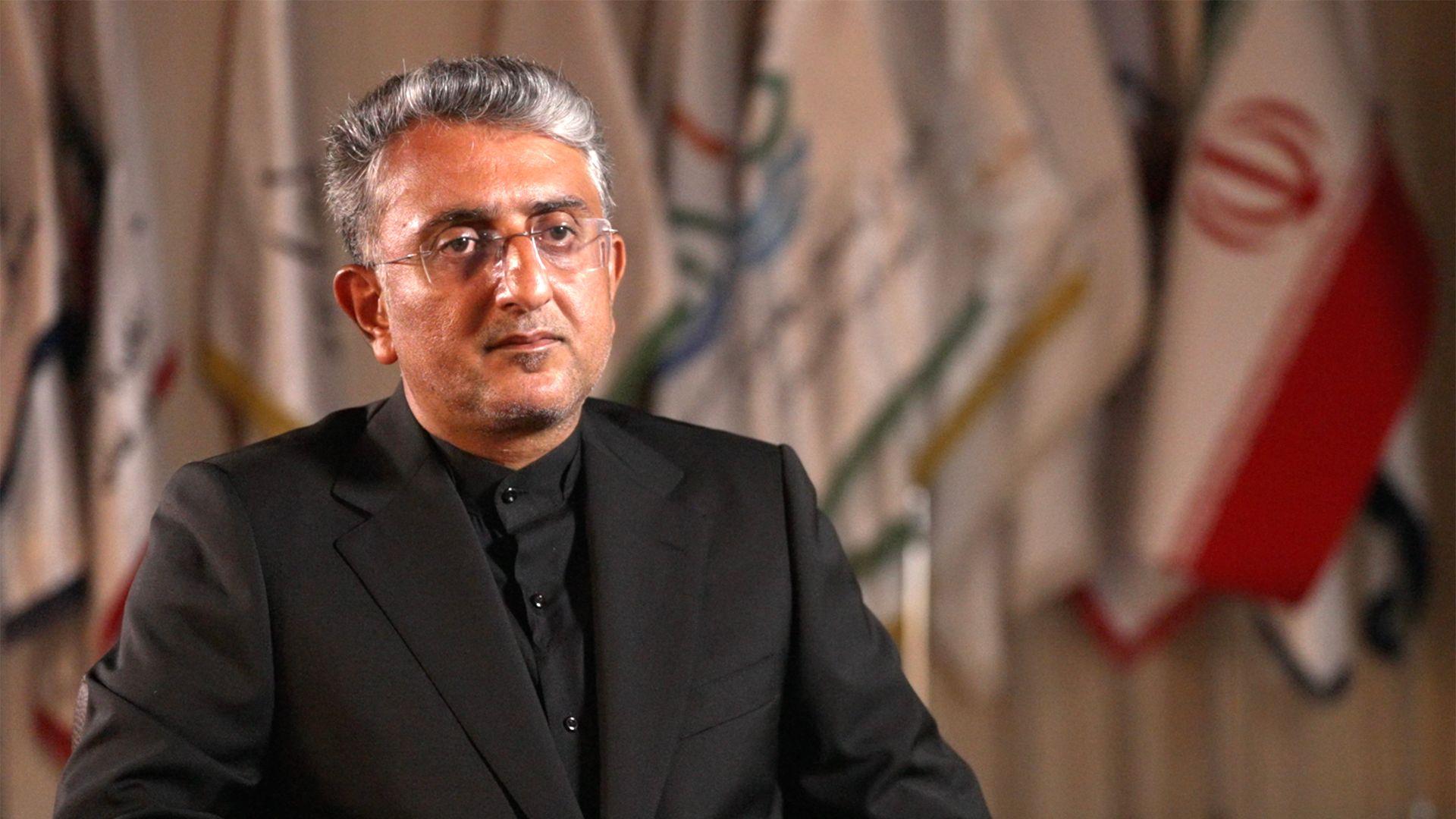 Zaplenjeni brodovi i lov na ajkule: BBC u Ormuskom moreuzu 6 Mehdi Nobani, gradonačelnik Bandar Abasa, u crnom odelu i crnoj košulji, sedi dok se iza njega vidi iranska zastava