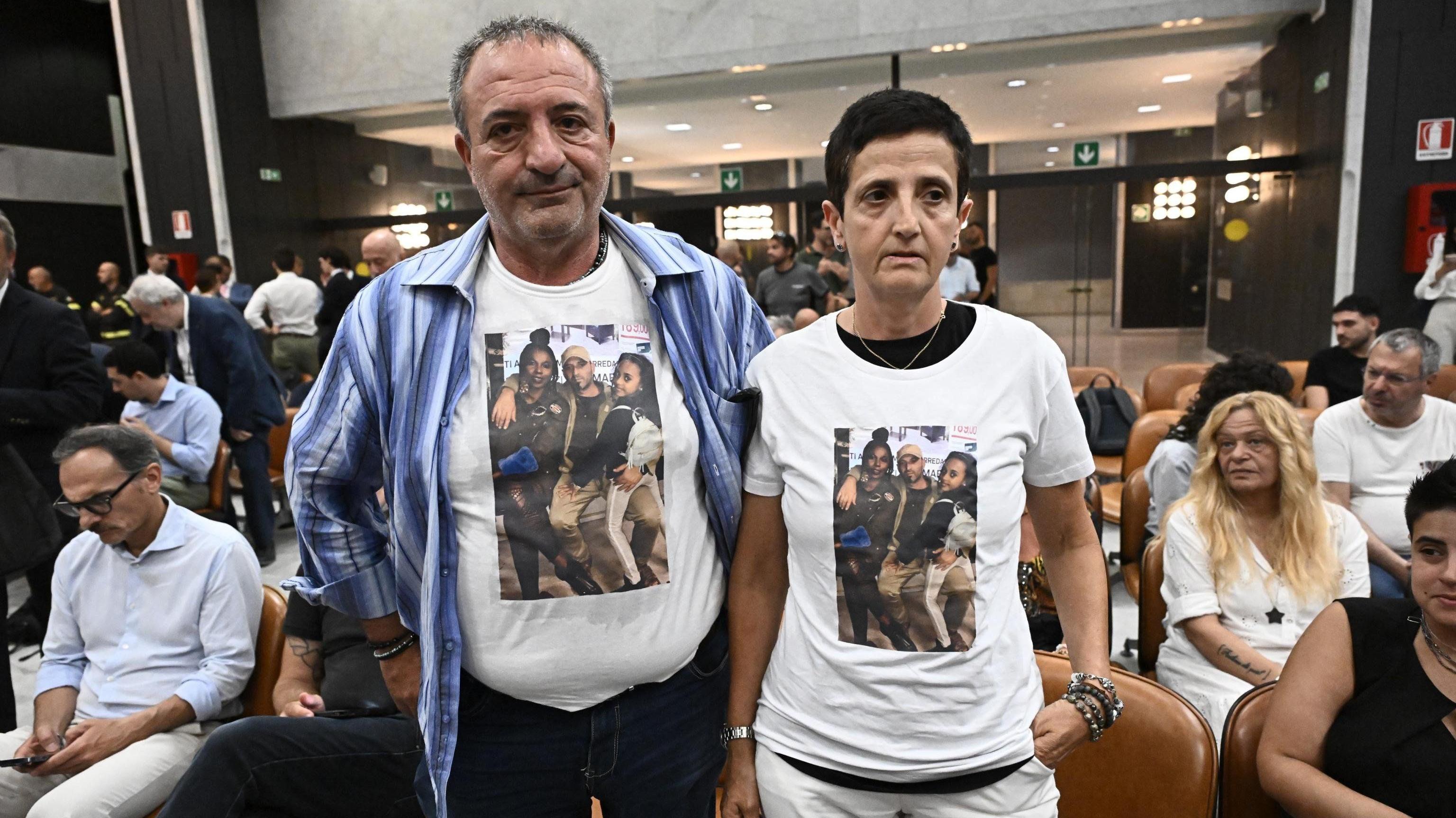 Rušenje mosta u Đenovi: Zatvorske kazne za italijanske zvaničnike 4 Muškarac i žena na sudu u majicama sa fotografijama nastradalih članova porodice