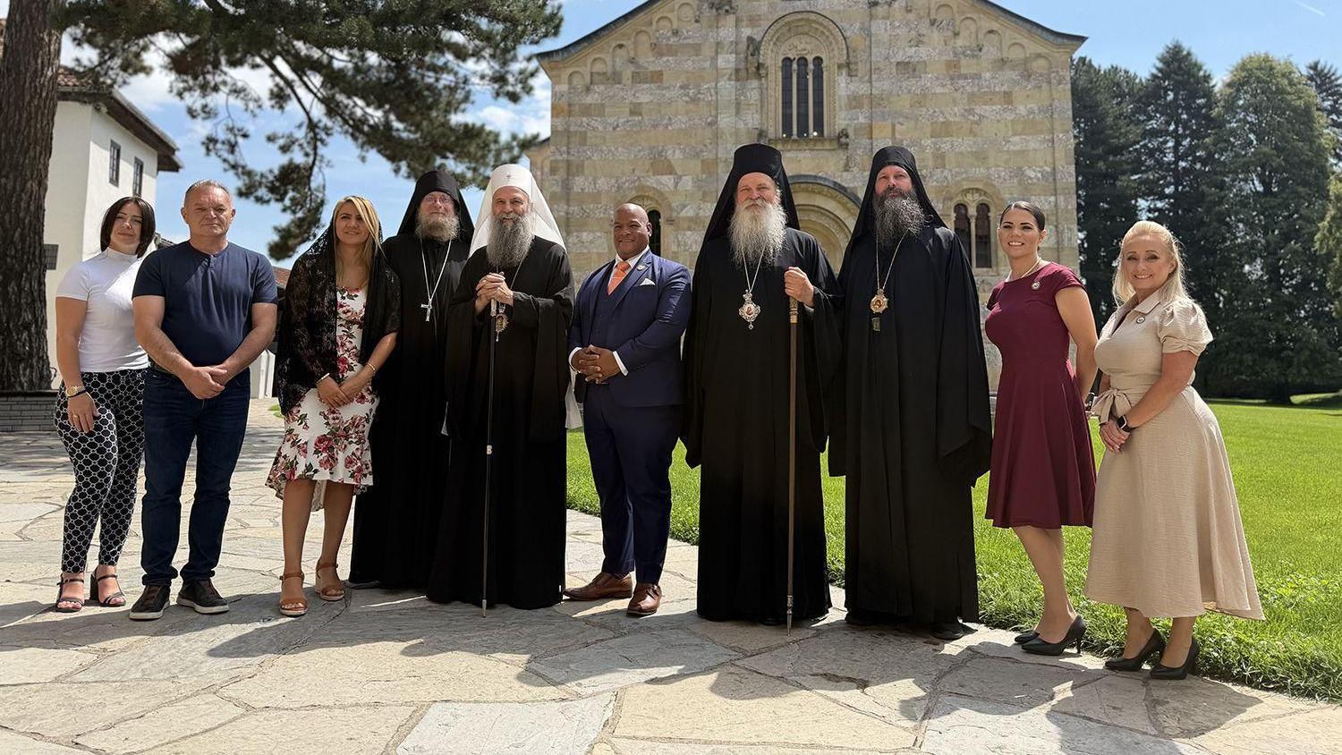 O pastoru Marku Bernsu: Kako je Vučić postao 'duhovni diplomata' 4 Grupa ljudi ispred crkve, pravoslavni sveštenici, žene i u sredini muškarac u plavom odelu