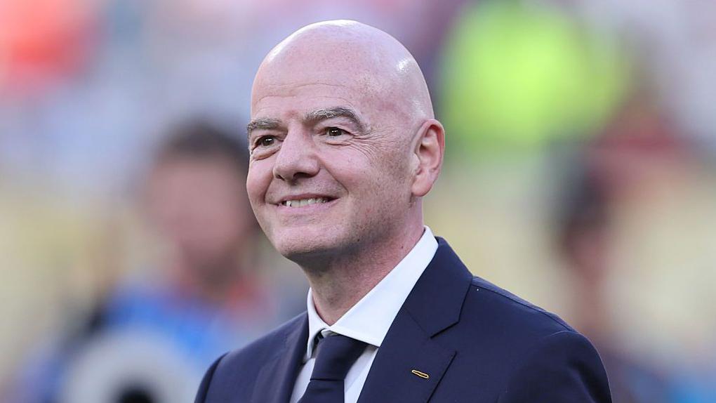 Infantino odgovorio kritičarima: 'Meditirajte, molite se ili gledajte fudbal' 1 Head and shoulders of a smiling Gianni Infantino, wearing a dark suit and tie