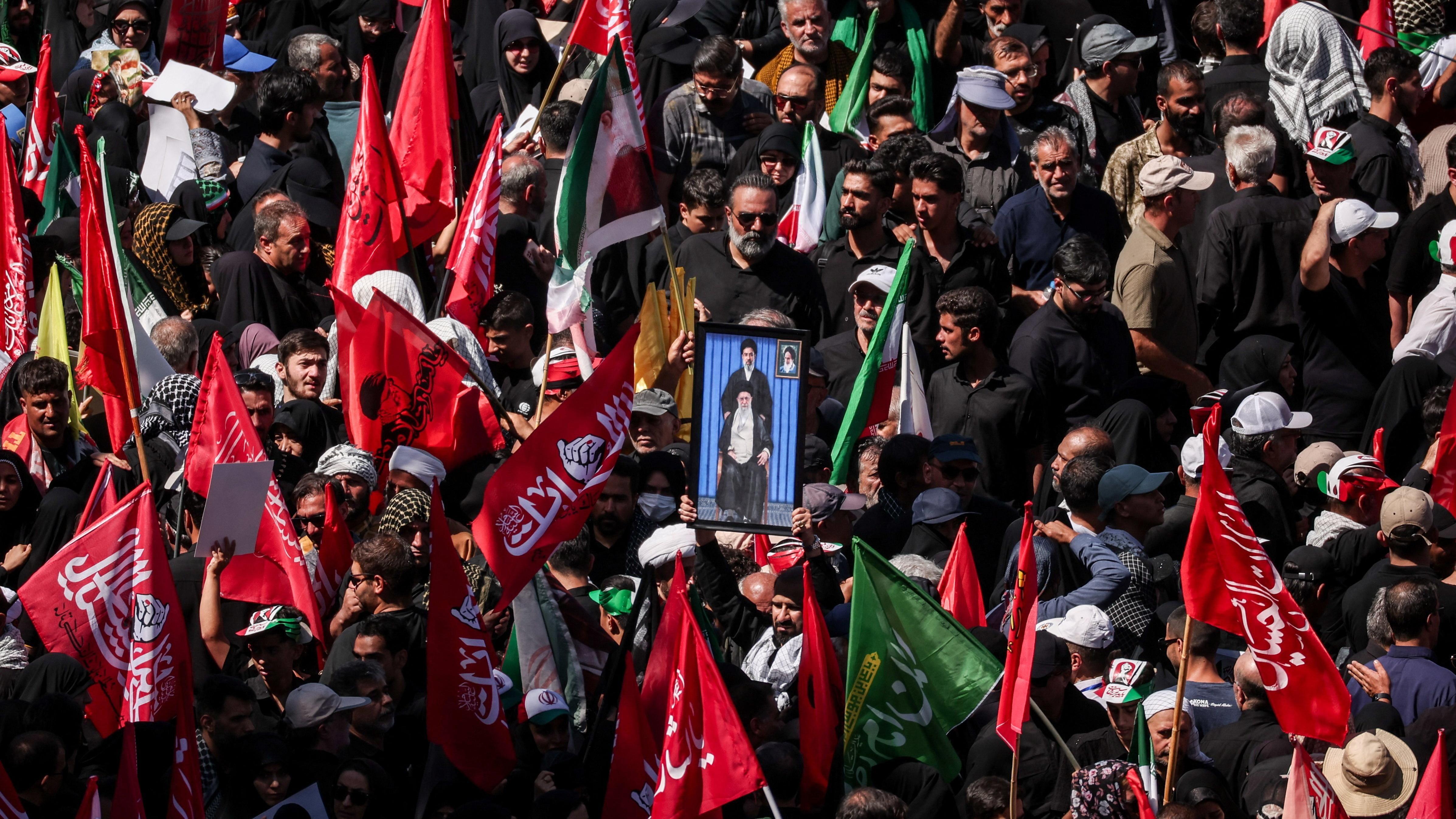 Amerika pokrenula nove napade, pošto je Iran ponovo zatvorio Ormuski moreuz 2 Mourners gather for the burial of Iranian Supreme Leader Ali Khamenei in Mashhad. Many are carrying red flags with Arabic script and in the centre a man holds a picture of a sitting Khamenei, with his son Mojtaba standing above him.