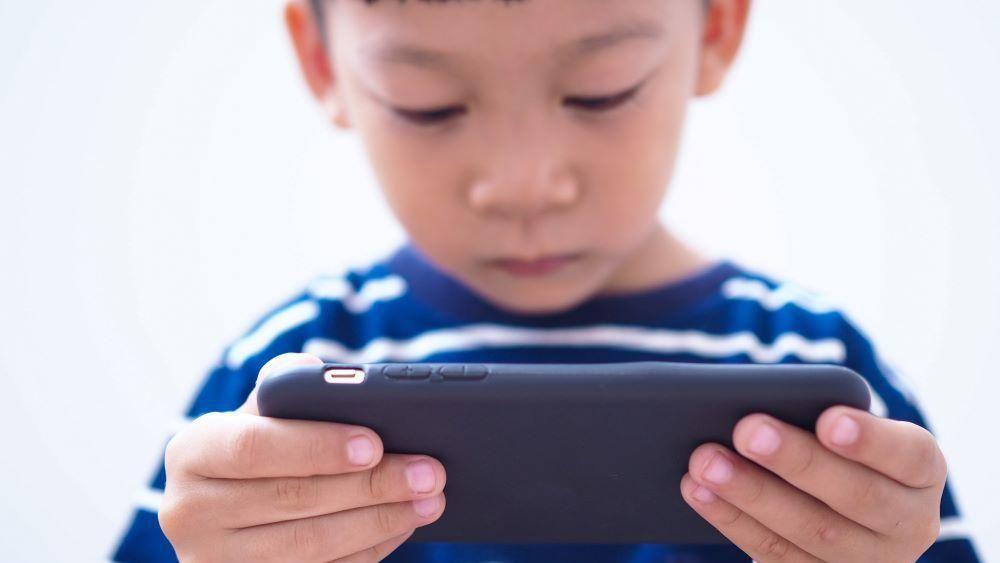 Dečak gleda u ekran mobilnog telefona